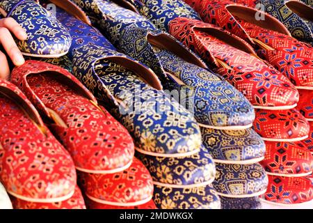 Bunte handgemachte Chappalls (Sandalen), die auf einem indischen Markt verkauft werden, handgefertigte Lederschuhe, traditionelle Schuhe. Stockfoto