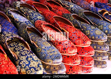 Bunte handgemachte Chappalls (Sandalen), die auf einem indischen Markt verkauft werden, handgefertigte Lederschuhe, traditionelle Schuhe. Stockfoto