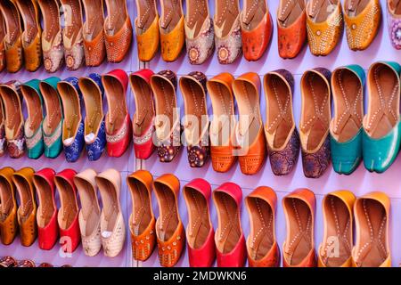 Bunte handgemachte Chappalls (Sandalen), die auf einem indischen Markt verkauft werden, handgefertigte Lederschuhe, traditionelle Schuhe. Stockfoto