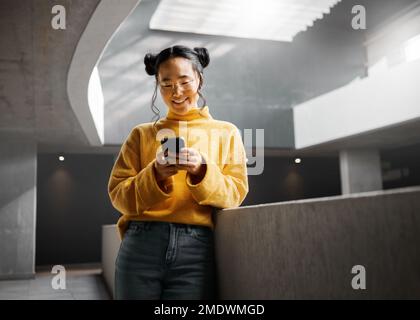 Glücklich, Frau und SMS am Telefon im Bürogebäude, entspannen Sie sich im Internet, suchen und lesen. Asiaten, Mädchen und Unternehmer Stockfoto