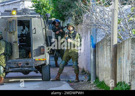 Nablus, Palästina. 23. Januar 2023. Israelische Soldaten stehen Wache, während andere Soldaten ein Haus umzingeln und durchsuchen, während des Überfalls im Dorf Salem östlich von Nablus im besetzten Westjordanland. Die israelische Armee brach in das Dorf Salem ein und durchsuchte mehrere Häuser der Palästinenser. Kredit: SOPA Images Limited/Alamy Live News Stockfoto