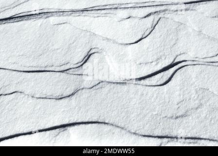 Weißer Schnee mit natürlich erzeugter Textur, Form und Muster als Hintergrund im Winter. Stockfoto