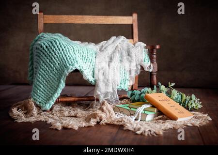 Digitale Fotografie für Neugeborene mit dunklem Vintage-Holz, Bank, Büchern und grünen Farben Stockfoto