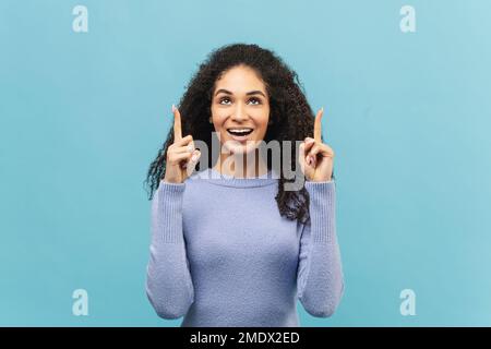Charmante junge afroamerikanische Frau zeigt Zeigefinger nach oben, fördert Neuheit isoliert auf blauem Hintergrund, Werbekonzept Stockfoto