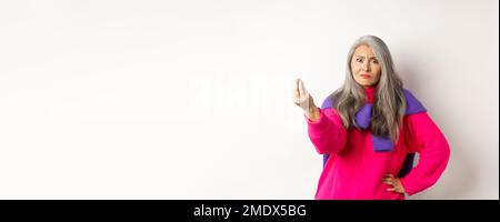 Lustige asiatische Frau starrte wütend und verwirrt, schüttelnde Finger, mürrisch vor weißem Hintergrund stehend Stockfoto