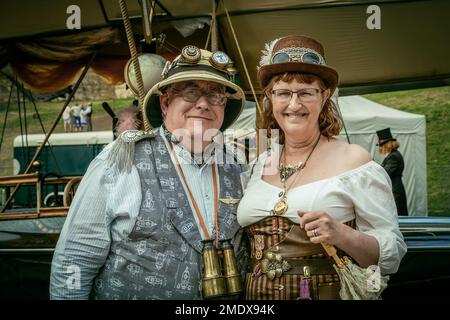 Ein Steampunk-Paar mittleren Alters lächelt direkt vor der Kamera. Reisen, Abenteuer, aktiv, Entdeckerkonzept. Stockfoto