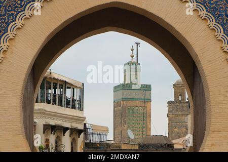 Fez, Marokko - Minarette von Marinid Bou Inania Madrasa durch das Stadttor von Bab Bou Jeloud. Monumentaler französischer Eingang in der alten Medina von Fez el Bali. Stockfoto