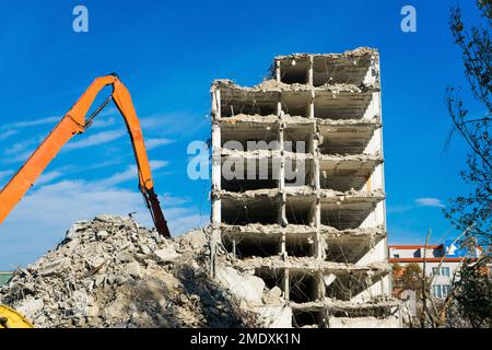 Abriss des alten Gebäudes mit Sloopkraan gegen den blauen Wolkenhimmel. Stockfoto