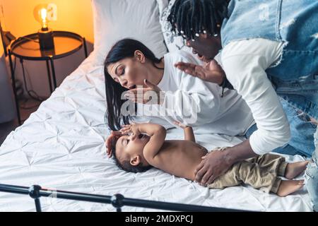 Junge Eltern und ihr kleiner Sohn küssen sich gegenseitig. Hochwertiges Foto Stockfoto