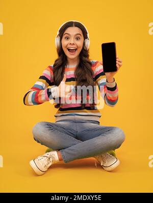 Ein erstaunlicher Teenager. Teenager Kind Mädchen hält Smartphone. Hipster Mädchen Typen SMS auf Handy, genießt Online-Kommunikation, Typen Feedback Stockfoto