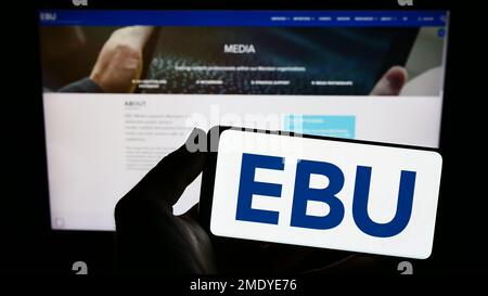 Person, die ein Smartphone mit dem Logo der Europäischen Rundfunkunion (EBU) auf dem Bildschirm vor der Website hält. Konzentrieren Sie sich auf das Display des Telefons. Stockfoto