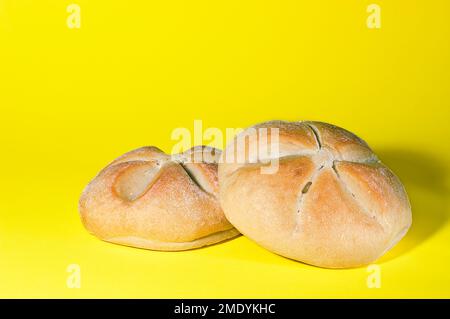 Zwei runde Brote frisch aus dem Ofen auf gelbem Hintergrund. Stockfoto