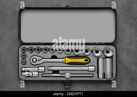 Werkzeugkasten für die Autoreparatur. Werkzeugsatz mit Knarre und Bits. Steckschlüssel und Ratschenköpfe. Werkzeugsatz auf grauem Hintergrund. Draufsicht, flach liegend. Stockfoto