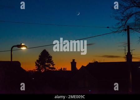 Fordingbridge, Hampshire, England, Vereinigtes Königreich, 23. Januar 2023, Wetter: Leuchtender orangefarbener Horizont über Dächern nach Sonnenuntergang, wenn die Temperatur unter den Gefrierpunkt fällt. Kredit: Paul Biggins/Alamy Live News Stockfoto