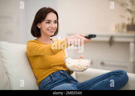 Junge Frau, die zu Hause Fernsehen, Filme mit Popcorn guckt Stockfoto