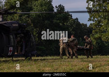 Sgt. Tyler Holloway von der 115. Artilleriebrigade in der Wyoming Army National Guard und SPC. Wyatt Walls vom 218. Artilleriegesiment in der Oregon Army National Guard beladen ein Opfer auf einen UH-60 Black Hawk beim National Best Warrior Competition, der auf dem Mailänder Freiwilligen stattfindet Training Site, Tennessee, 26. Juli 2022. Der Tag bestand aus einer Reihe von Veranstaltungen, zu denen die Unfallverhütung, ein Feuerruf und improvisierte Sprengstoffspuren gehörten. Der National Best Warrior Competition hat die besten Soldaten der Army National Guard. Stockfoto