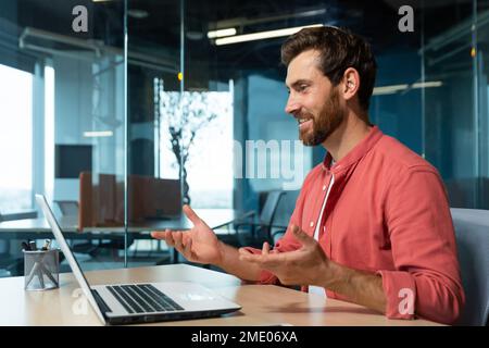 Videoanrufe von erfolgreichen und fröhlichen lächelnden Geschäftsleuten, Mann, der aus der Ferne mit einem Laptop spricht, während er im Büro sitzt, Online-Meetings mit Kollegen und Kundenbetreuung. Stockfoto