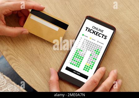 Nahaufnahme von weiblichen Händen mit Kreditkarte, die Karten für das Event-Kino per Handy bezahlen. Online-Reservierung von Theaterkarten für Shows. Stockfoto