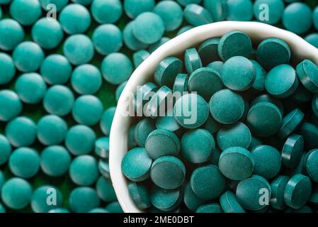 Green Organic Spirulina in Algen Pillen Tabletten Bambusholzlöffel reich an Eisen Nahaufnahme Super Food Konzept gesund. Stockfoto