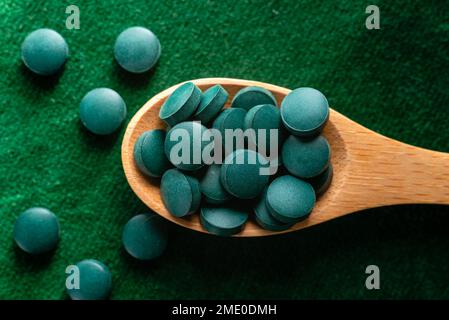 Green Organic Spirulina in Algen Pillen Tabletten Bambusholzlöffel reich an Eisen Nahaufnahme Super Food Konzept gesund. Stockfoto