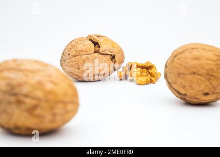 Walnuss mit Blattisolat. Walnüsse geschält und ungeschält mit Blättern auf weiß. Seitenansicht der Walnussmutter. Mit Beschneidungspfad. Stockfoto