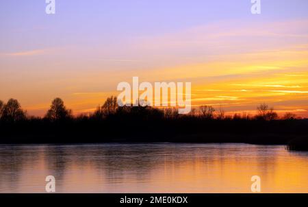 Die Sonne geht über einem gefrorenen See an den Stanwick Lakes in Northamptonshire unter. Foto: Montag, 23. Januar 2023. Stockfoto