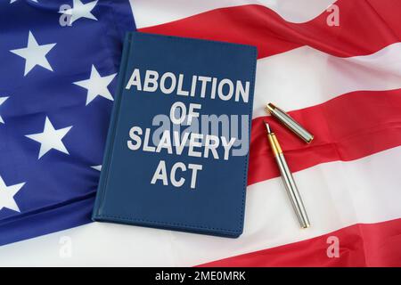 Regelkonzept. Auf der US-Flagge liegt ein Stift und ein Buch mit der Inschrift - Aberkennung der Sklaverei Stockfoto