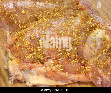 Rohes, entbeintes Hähnchenfilet, gewürzt mit getrockneten Gemüsemischungen. Stockfoto