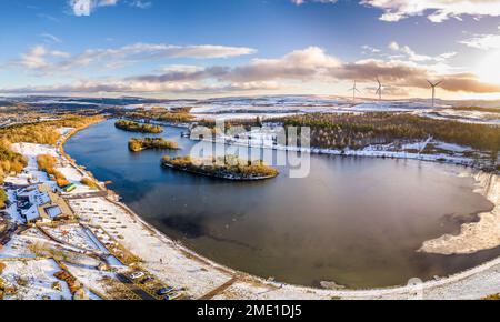 Panoramablick aus der Vogelperspektive auf einen halbgefrorenen See, umgeben von Schnee. Stockfoto