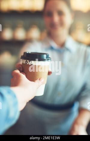 Komm und hol dir deine frische Tasse. Ein Gast, der eine Tasse Kaffee von einem Barista in einem Café trinkt. Stockfoto