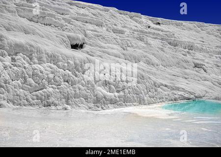 Blick auf die natürlichen Terrassen in Pamukkale an einem Sommertag. Nahaufnahme von Kalkstein und Wasser, das darüber fließt. Stockfoto