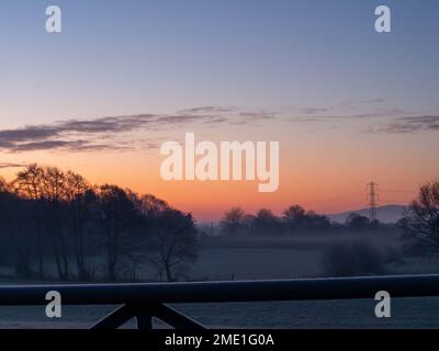 Sonnenaufgang an einem kalten und frostigen Morgen mit tiefliegendem Nebel über den Feldern von East Cheshire mit Blick auf das Bauerntor. Stockfoto