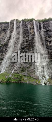 Eine vertikale Aufnahme eines wunderschönen schaumigen Wassers, das unter dem grauen Himmel über die Felsen fällt Stockfoto