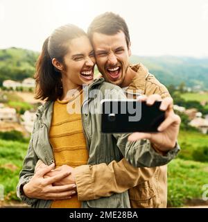 Finden Sie die Person, die das Beste aus Ihnen herausholt. Ein liebevolles Paar, das draußen ein Selfie macht. Stockfoto