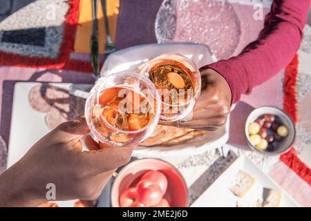 Von oben wurden unbekannte afroamerikanische Freundinnen gekürzt, die am Tisch saßen und beim Picknick im Garten Gläser klirten Stockfoto