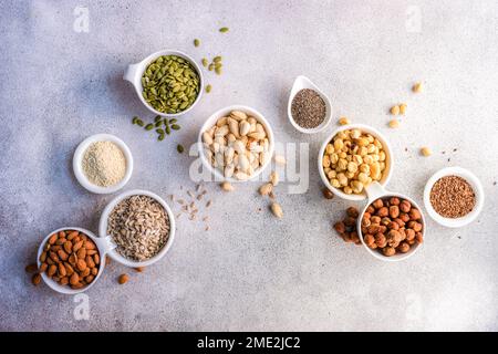 Draufsicht der Schüsseln mit Nüssen und Samen auf Betonhintergrund Stockfoto