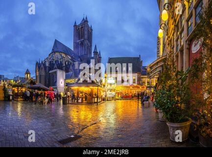 Weihnachtsmarkt in Gent mit leuchtenden Lichtern in der Abendstadt in der Nähe von alten Gebäuden und Straßenbahn Stockfoto