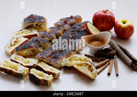 Bild für Ihre Werbung Apfelstrudel Hefeteig auf dem Tisch mit Zutaten Zimt Muskatnuss 2 rote Äpfel auch geschnitten fertig gekochtes Dessert leichter Hintergrund leckeres hausgemachtes Essen gesund Stockfoto
