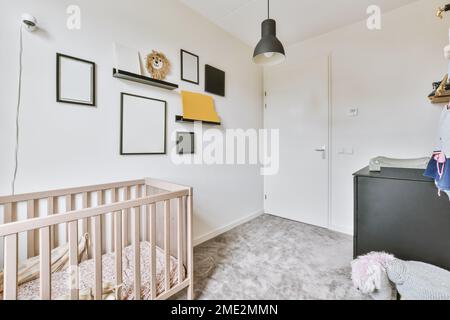 Leere Rahmen und Regale mit Handwerk, das an der Wand über dem Kinderbett in einem leichten Kinderzimmer hängt Stockfoto