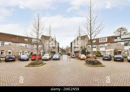 Autos, die auf Asphaltparkplätzen in der Nähe von gepflasterten Straßen und Ziegelgebäuden geparkt sind Stockfoto