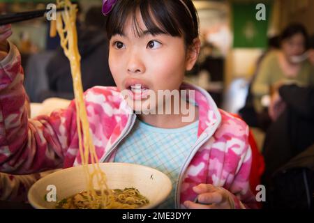 Ein asiatisches Mädchen isst Ramen in einem Restaurant vor Ort Stockfoto