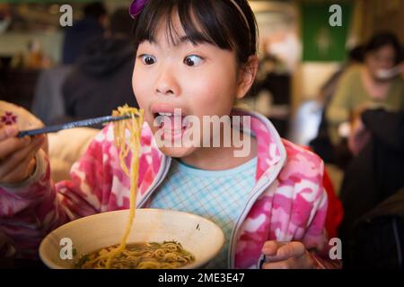 Ein asiatisches Mädchen isst Ramen in einem Restaurant vor Ort Stockfoto