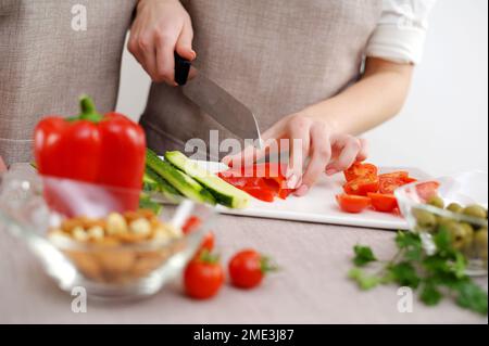 Nahaufnahme des zugeschnittenen Bretts und Zusammenschneiden von Gemüse in der Küche zur Zubereitung von Mahlzeiten zu Hause. Vegetarisches gesundes Essen Paar Zubereitung einer Mahlzeit mit gezackter Paprika Stockfoto