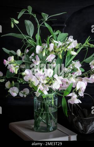 Sweetpea-Blumen im Glasgefäß auf Tagebuch Stockfoto