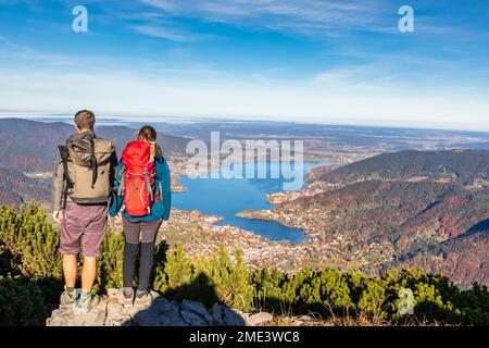 Deutschland, Bayern, Rottach-Egern, Wanderpaar, das den Blick auf den Tegernsee und die umliegenden Städte vom Gipfel des Wallbergs aus bewundert Stockfoto