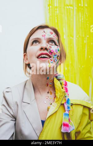 Glückliche Frau mit Aufklebern im Gesicht vor einer zweifarbigen Wand Stockfoto