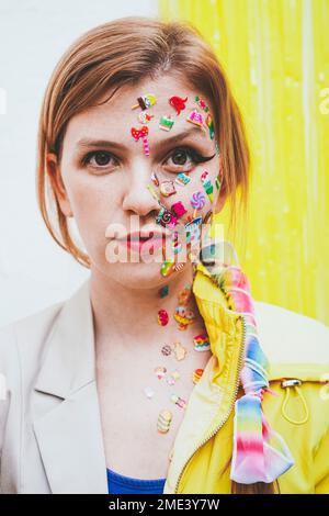 Frau mit Aufklebern im Gesicht vor einer zweifarbigen Wand Stockfoto