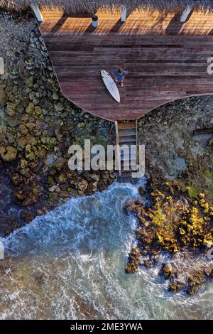 Drohnenansicht eines Mannes mit Surfbrett auf der Terrasse Stockfoto