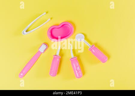 Kinderzahnarzt-Set. Gelber Hintergrund. Flach verlegt. Medizin, Stomatologie, Kinderspielzeug Konzept. Stockfoto