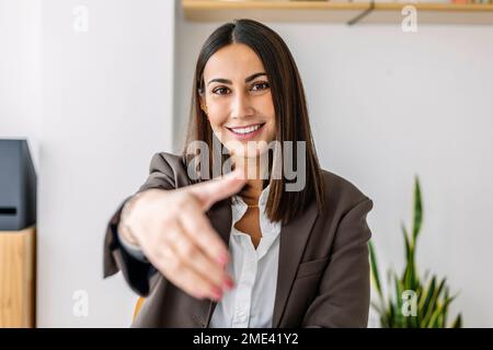 Lächelnder Anwerber, der im Büro eine Handschlag-Geste macht Stockfoto